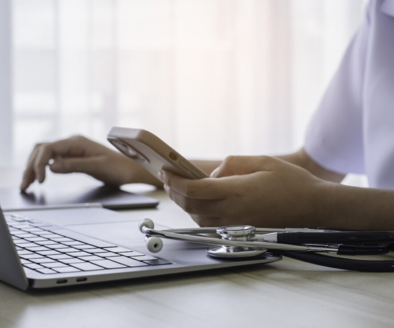 Doctor using mobile smartphone and work on digital tablet with laptop computer in modern office at clinic or hospital. Medical technology, telemedicine concept.